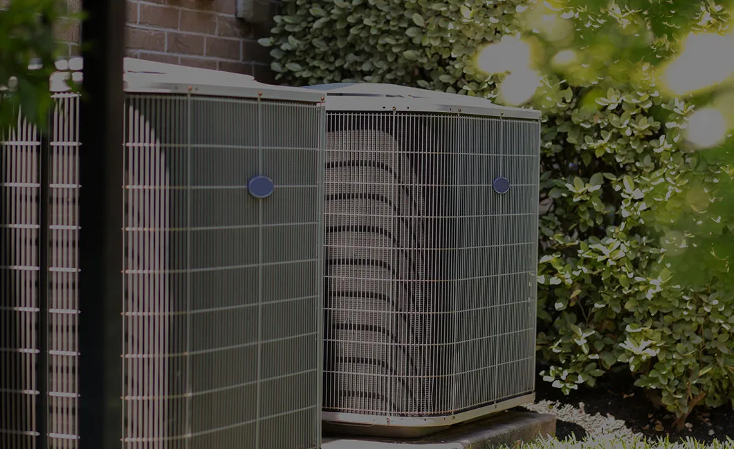 Two Carrier air conditioning condensers beside a home