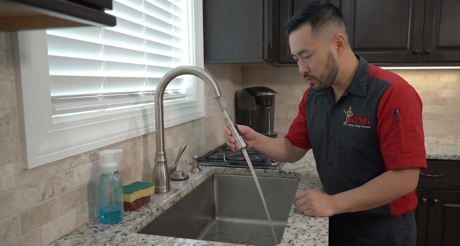 A King plumber repairing a kitchen faucet